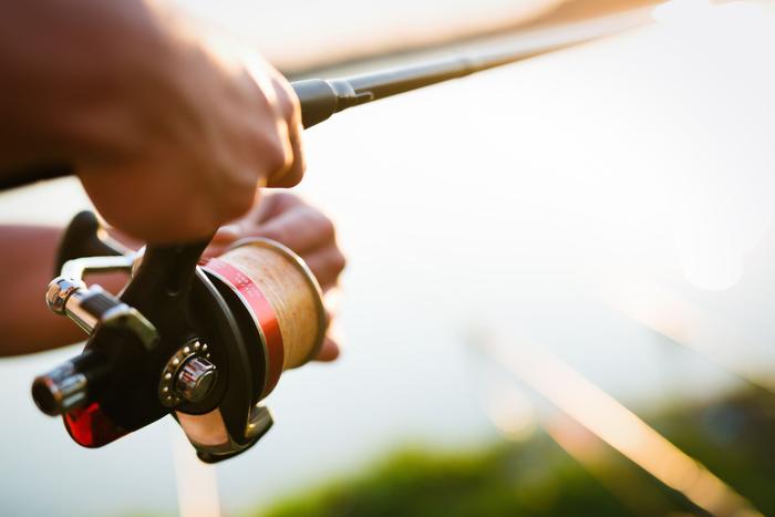 Hands working a spinning reel