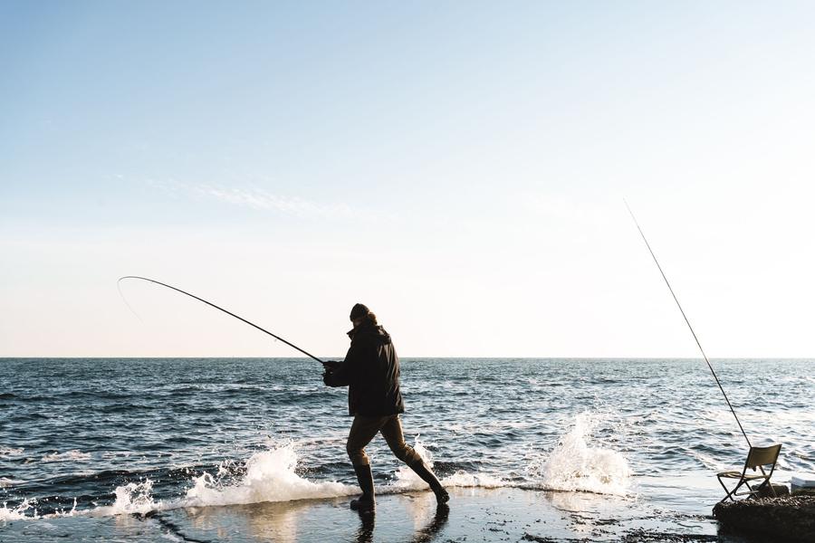 An angler fights a fish at the water's edge
