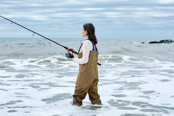 An angler in waders fishing in the ocean surf