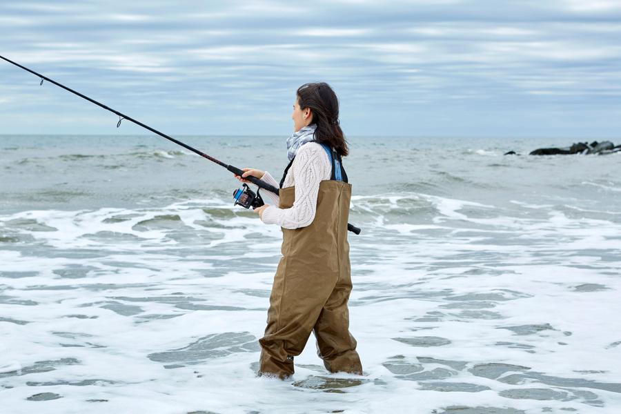 An angler in waders fishing in the ocean surf